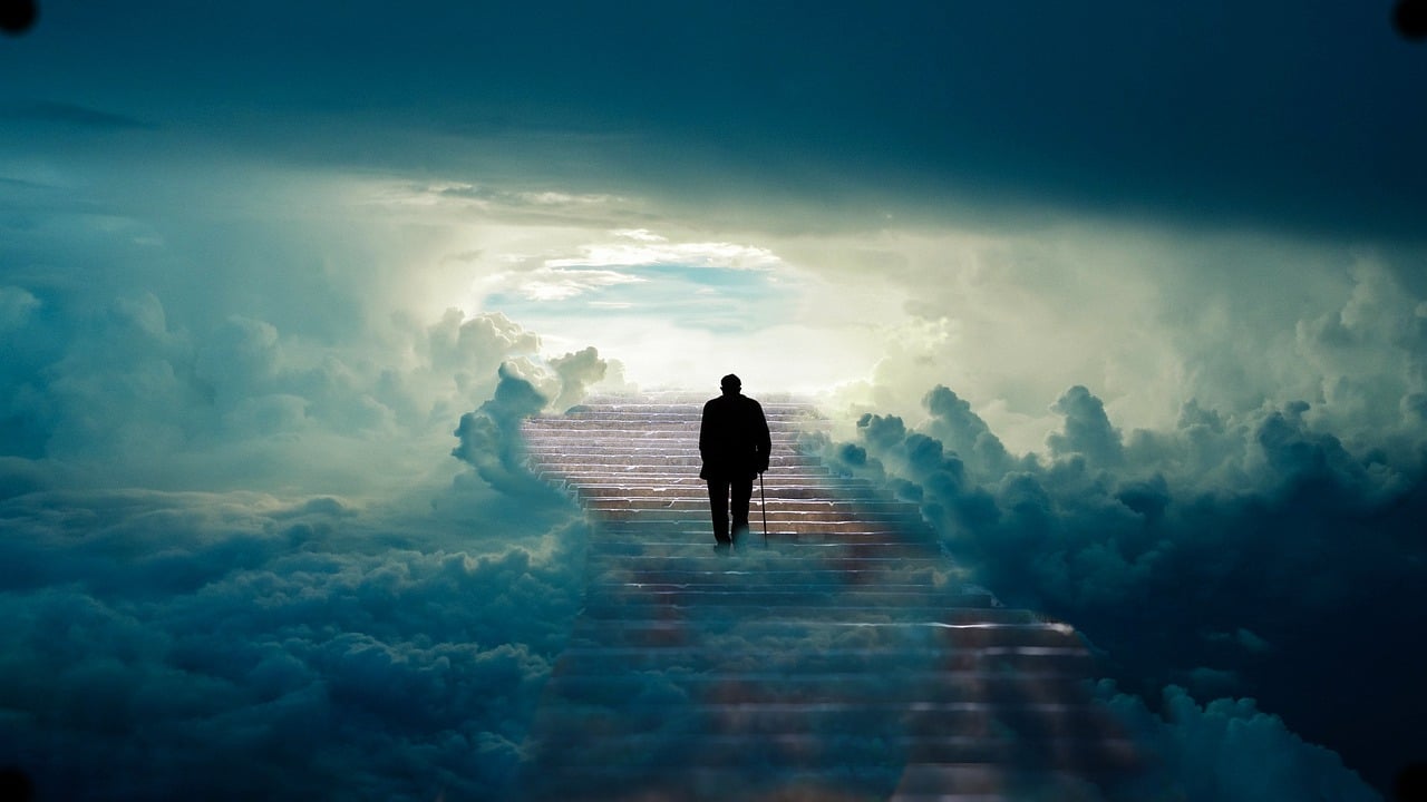 Imagen de un hombre de la tercerar edad con un astón caminando hacia el cielo con nubes color azul y negro, simbolizando la muerte para el articulo de etapas de el duelo de muerte de Carl rogers.