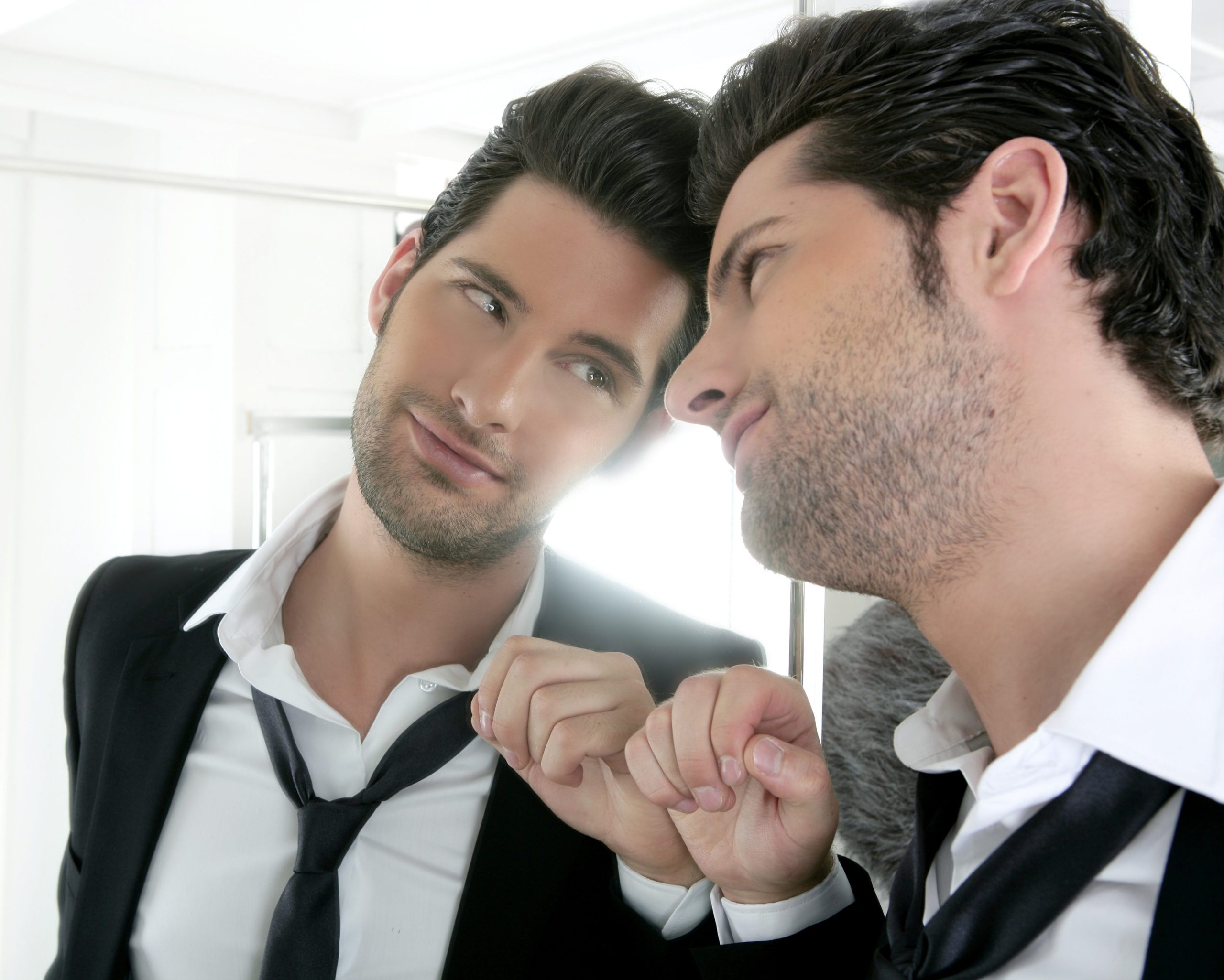 Foto de hombre narcisisita con traje mirandose al espejo